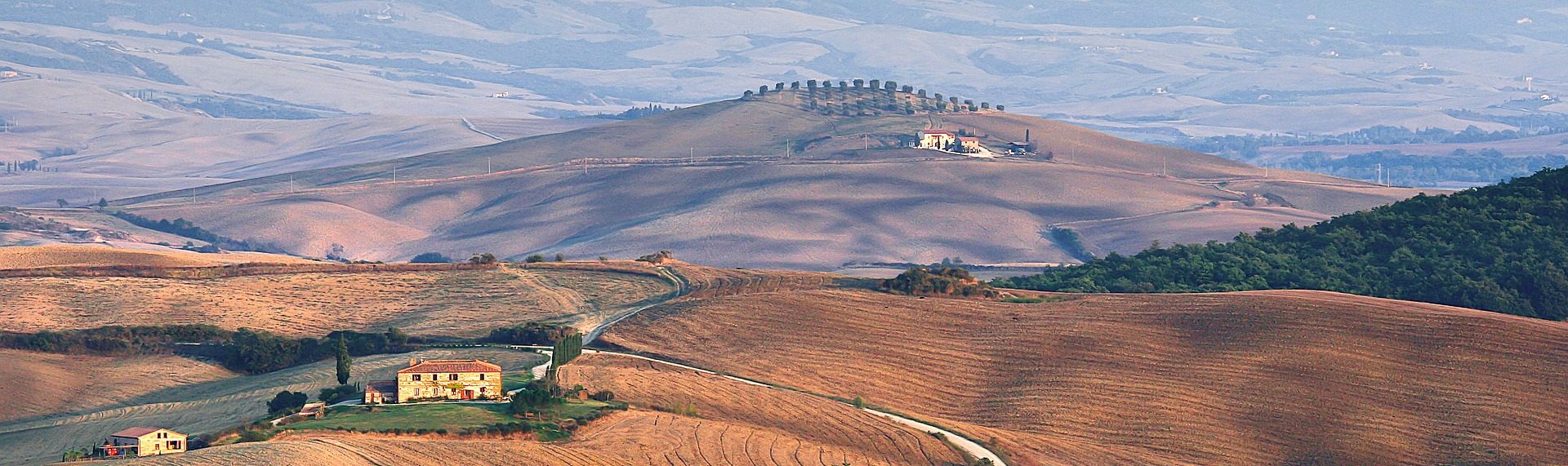 Colline toscane dai toni caldi con casali e cipressi
